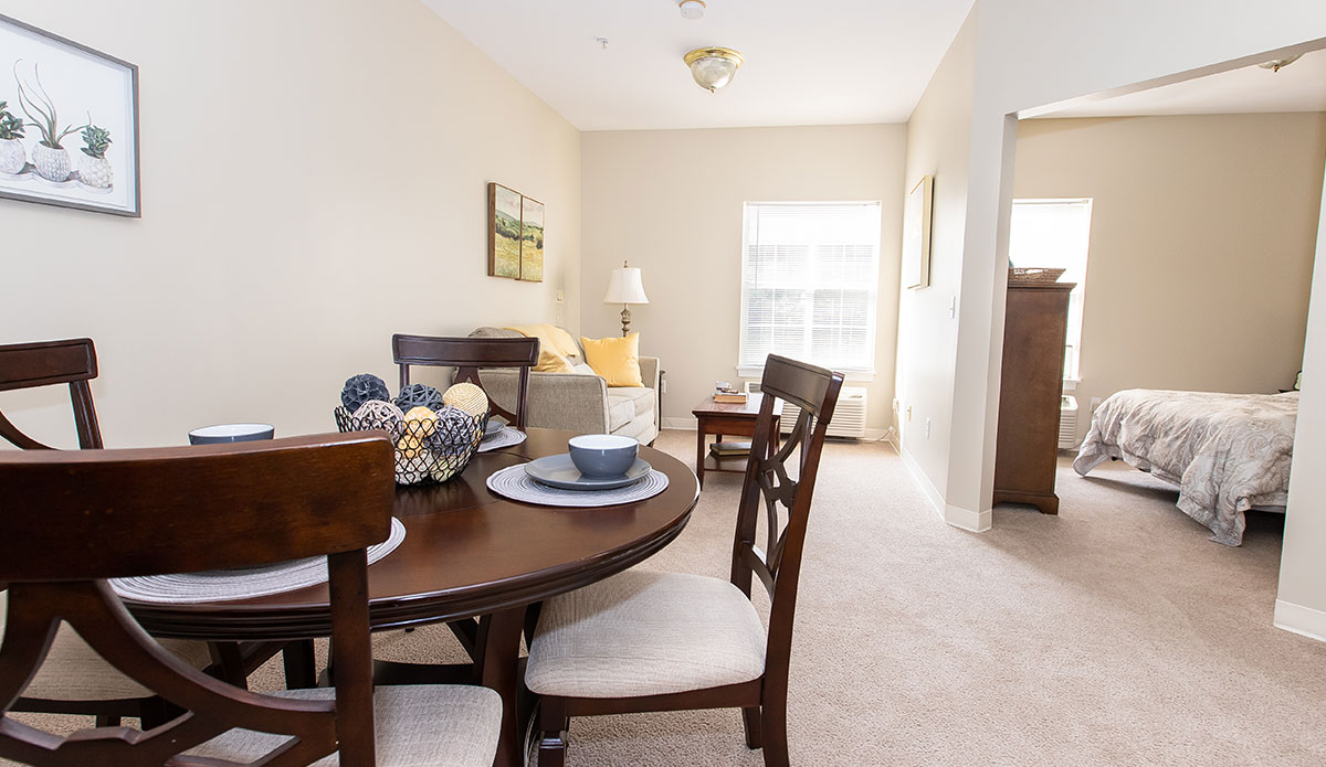 A bright dining room with a stylish table and four matching chairs set for a meal.