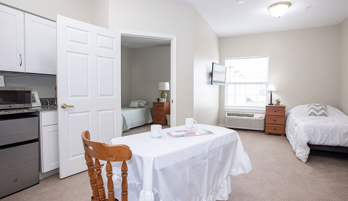 A bedroom setup with a bed, a fridge, and a microwave, ideal for relaxation and snacks.