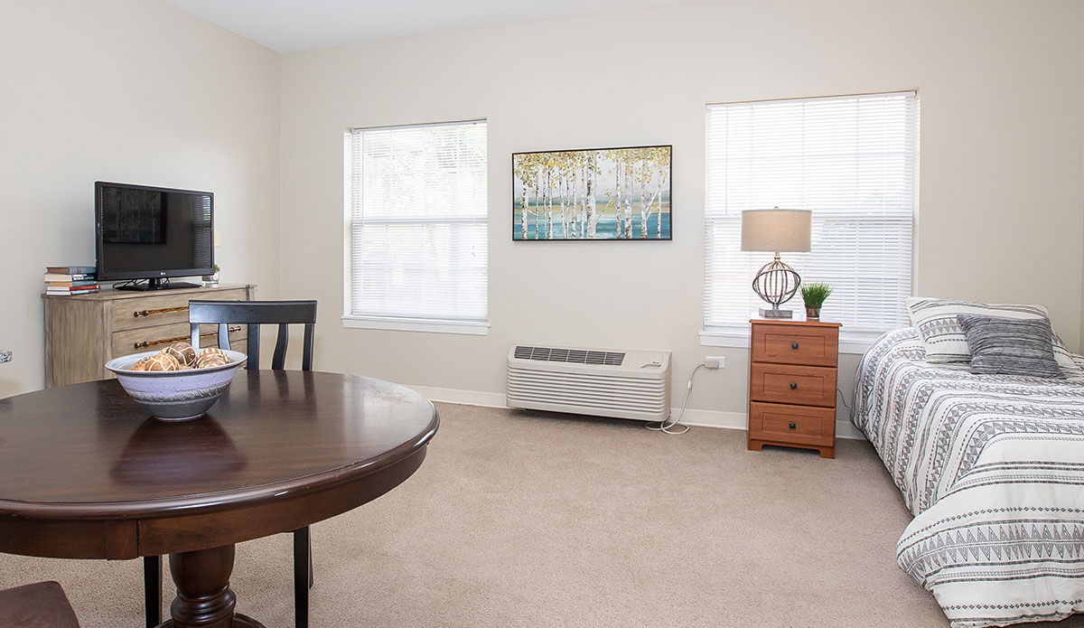 A bedroom setup with a table, a chair, and a television, perfect for relaxation and comfort.