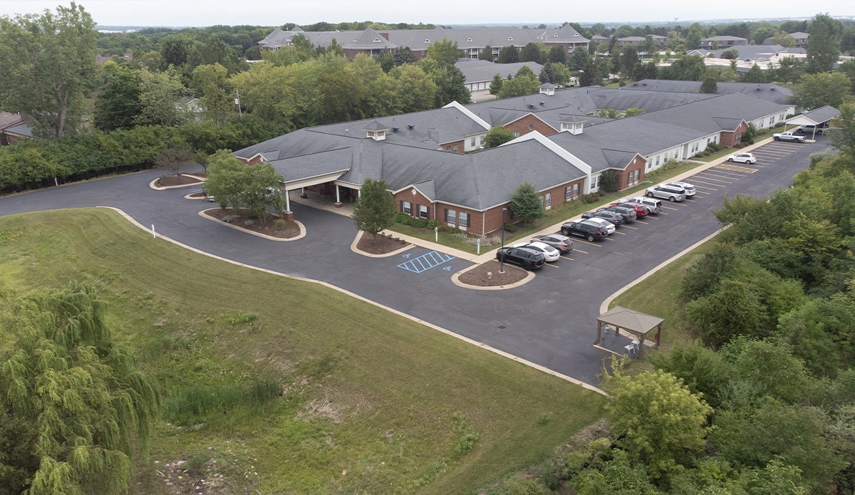Aerial view of the parking lot at a senior living community, showing parked cars and surrounding greenery.