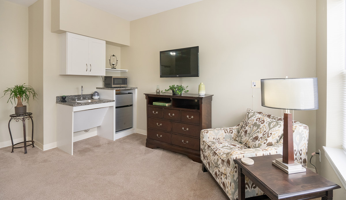 A small room showcasing a bed, a chair, and a television for comfort.