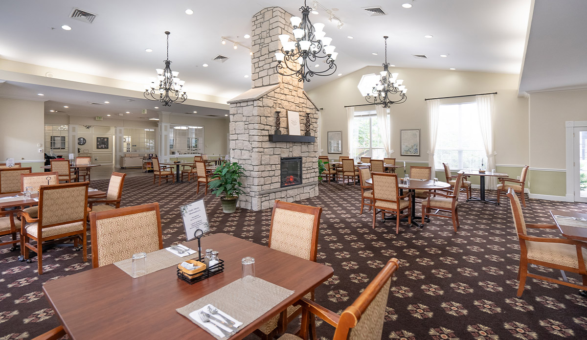 dining room in a senior living community, featuring tables set for meals and warm, inviting decor.