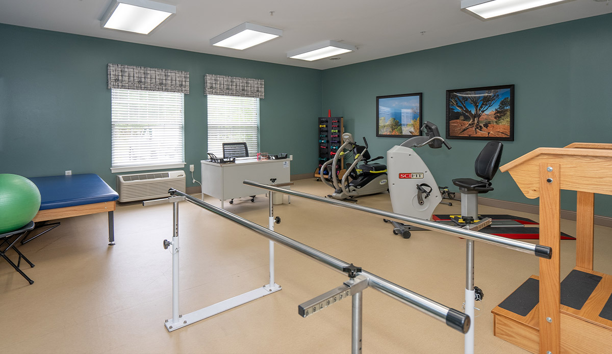 A room featuring exercise equipment alongside a desk, creating a space for fitness and productivity.