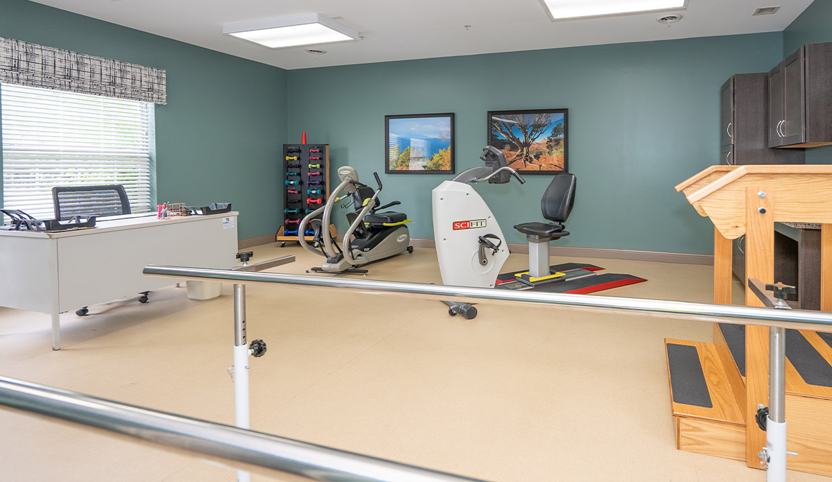 A room featuring exercise equipment alongside a desk, creating a space for fitness and productivity.