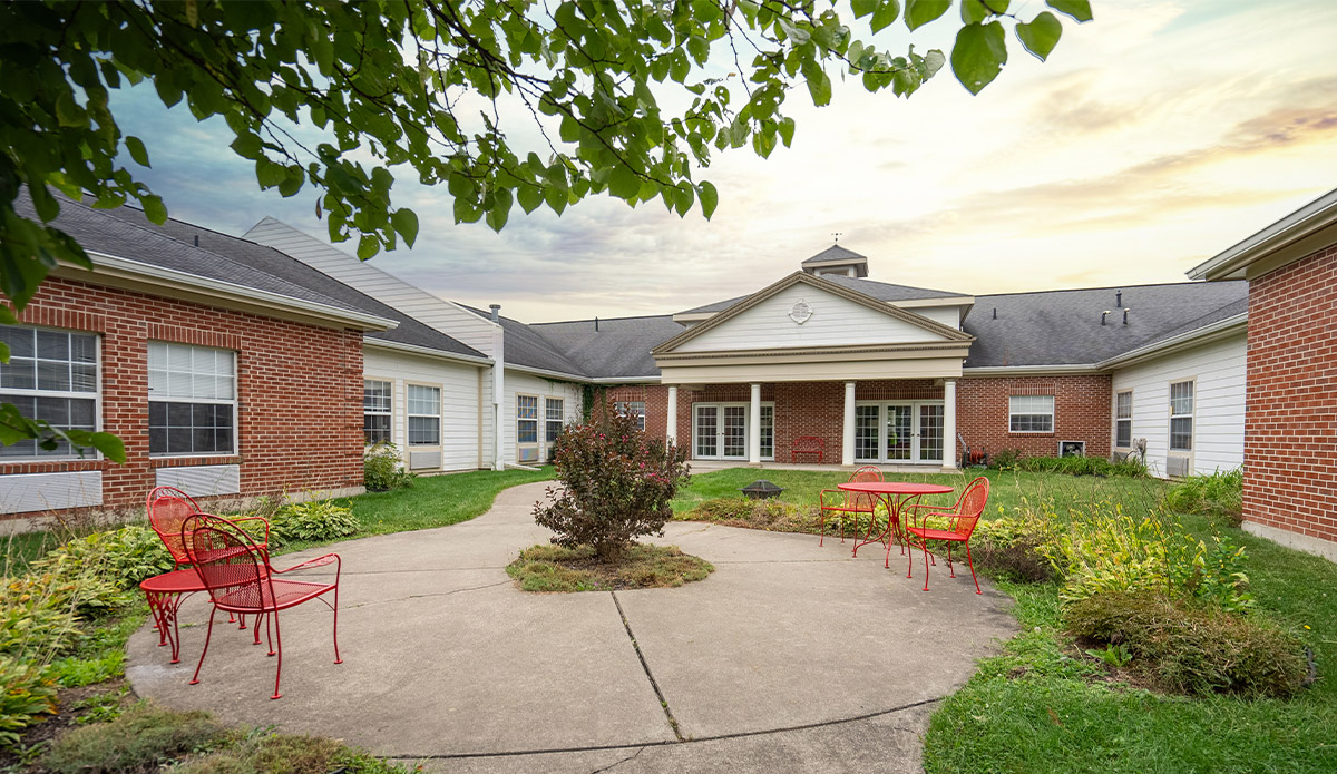A vibrant courtyard with red chairs surrounding a classic brick building.